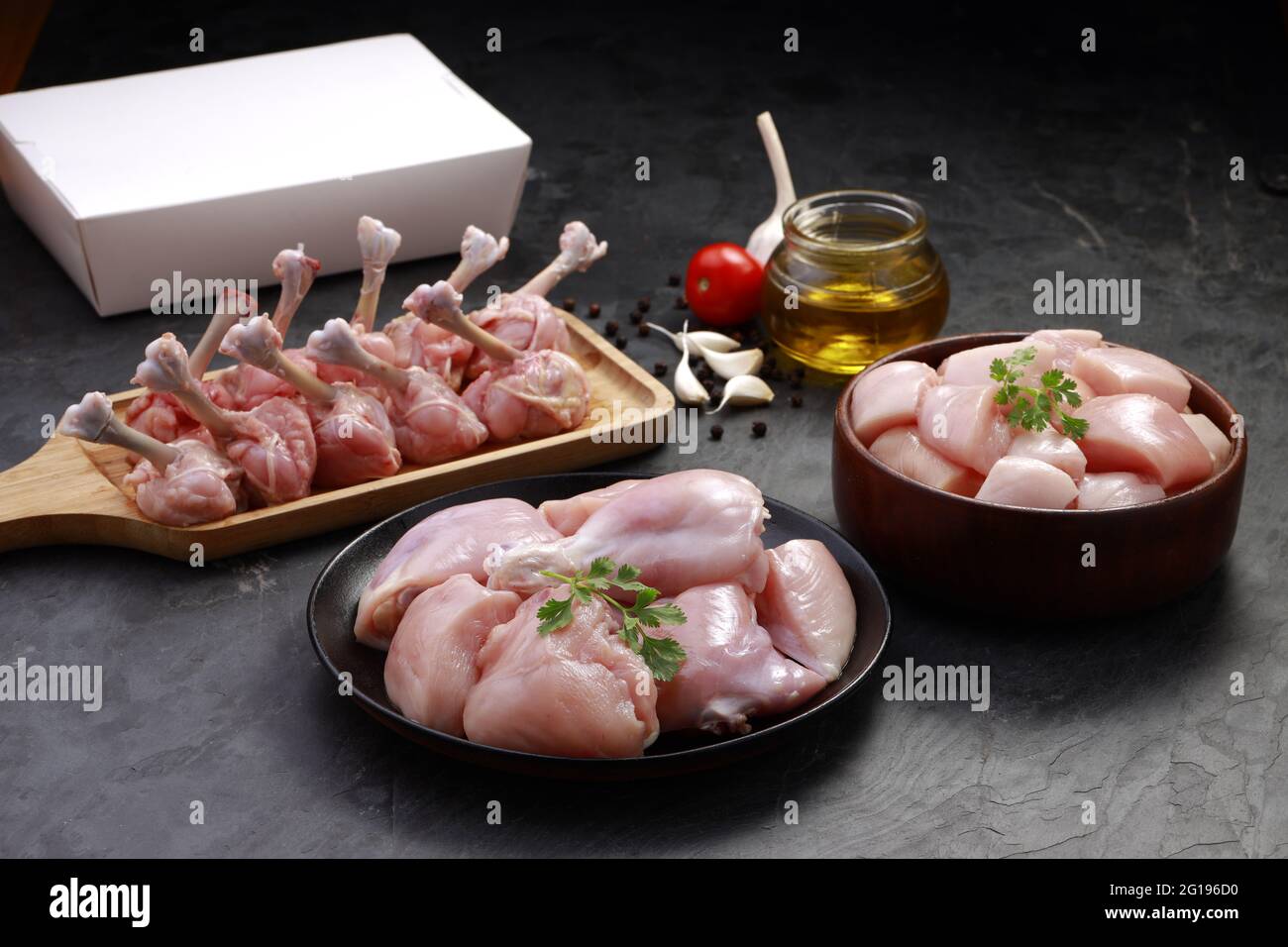 Combo de coupes de poulet cru, combinaison de coupes de poulet biriyani, coupes de poulet frite et lollipop de poulet disposés sur une planche en bois avec feuille de coriandre, gar Banque D'Images