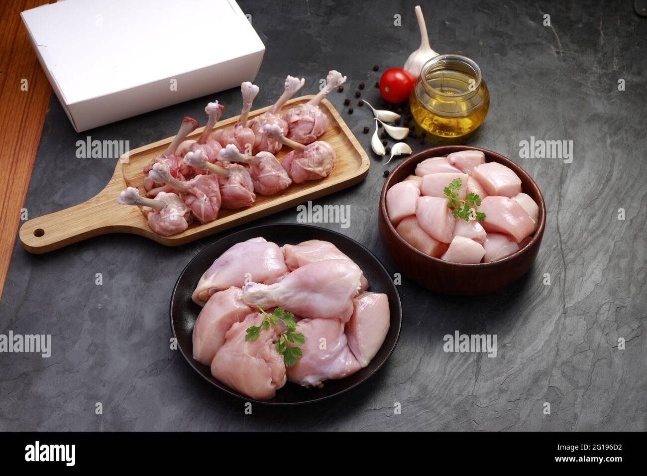 Combo de coupes de poulet cru, combinaison de coupes de poulet biriyani, coupes de poulet frite et lollipop de poulet disposés sur une planche en bois avec feuille de coriandre, gar Banque D'Images