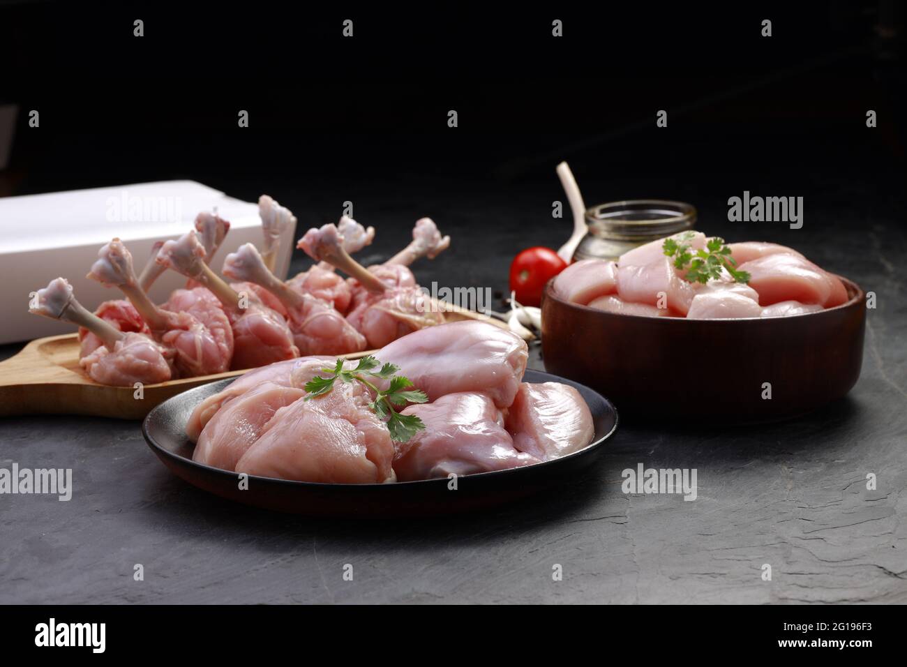 Combo de coupes de poulet cru, combinaison de coupes de poulet biriyani, coupes de poulet frite et lollipop de poulet disposés sur une planche en bois avec feuille de coriandre, gar Banque D'Images