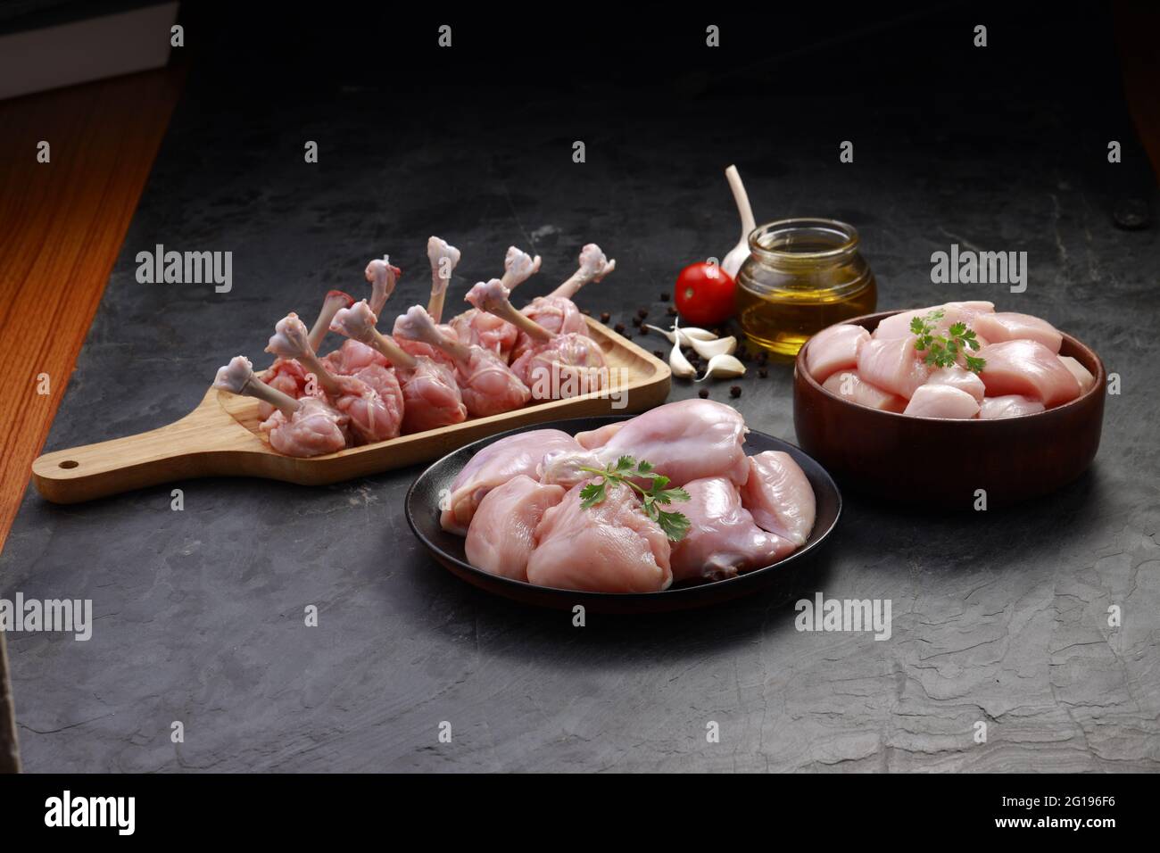 Combo de coupes de poulet cru, combinaison de coupes de poulet biriyani, coupes de poulet frite et lollipop de poulet disposés sur une planche en bois avec feuille de coriandre, gar Banque D'Images