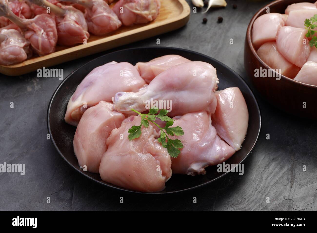 Combo de coupes de poulet cru, combinaison de coupes de poulet biriyani, coupes de poulet frite et lollipop de poulet disposés sur une planche en bois avec feuille de coriandre, gar Banque D'Images