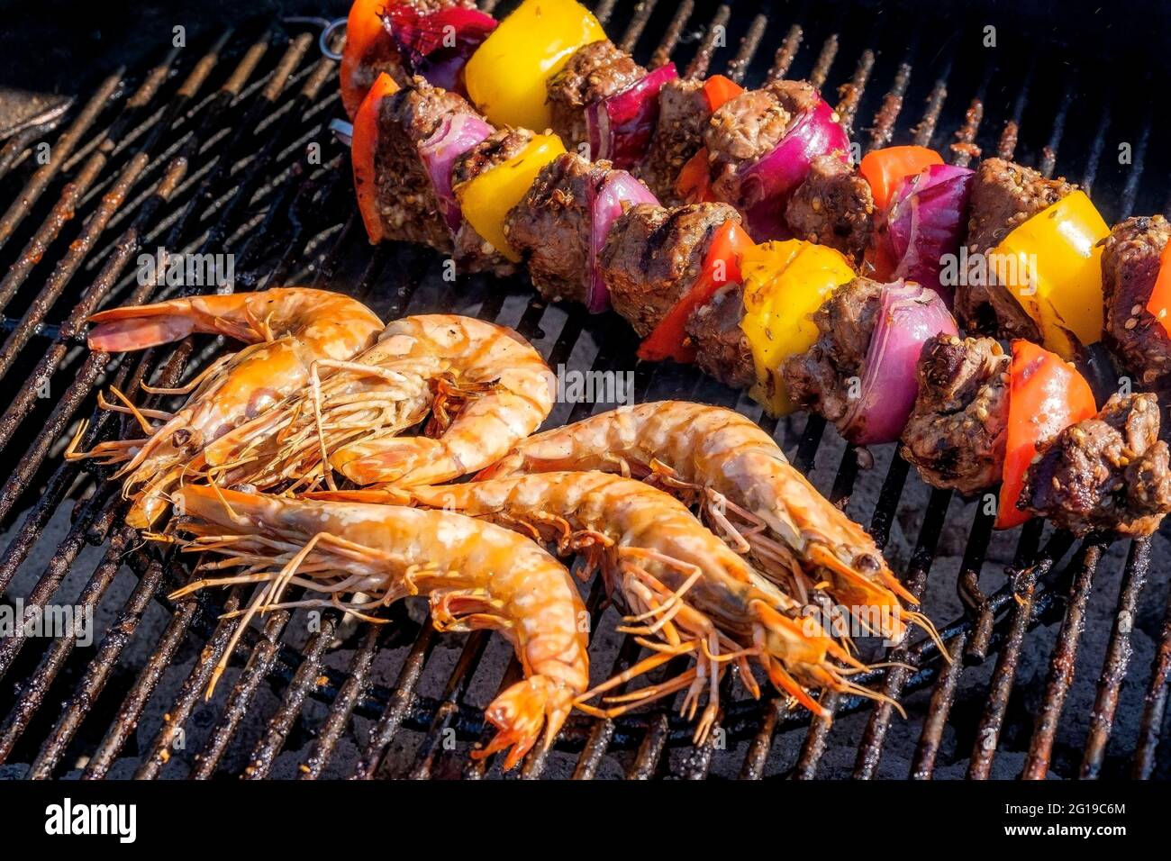 Les crevettes et les Kebabs d'agneau cuisent sur un barbecue. Banque D'Images