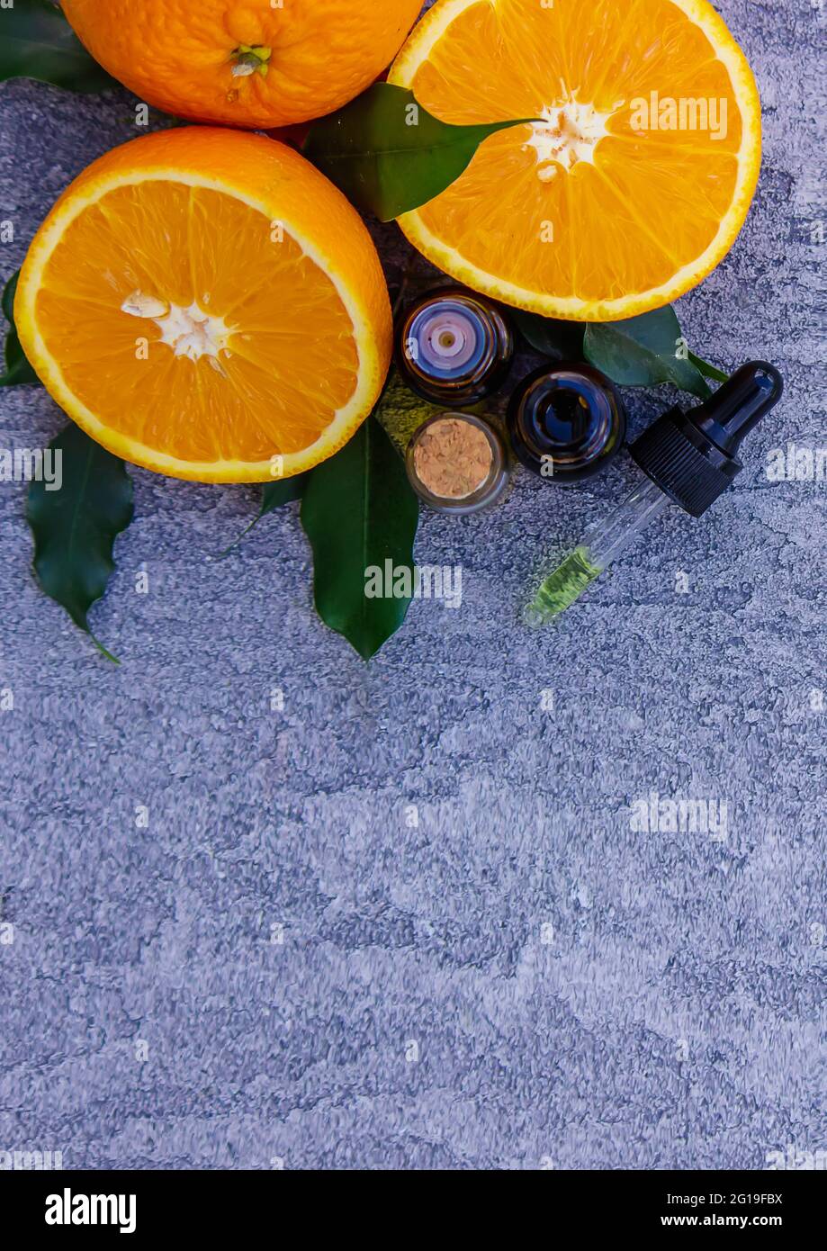 Huile d'orange essentielle dans une bouteille, morceaux de fruits frais sur le fond. Saveurs naturelles. Mise au point sélective Banque D'Images