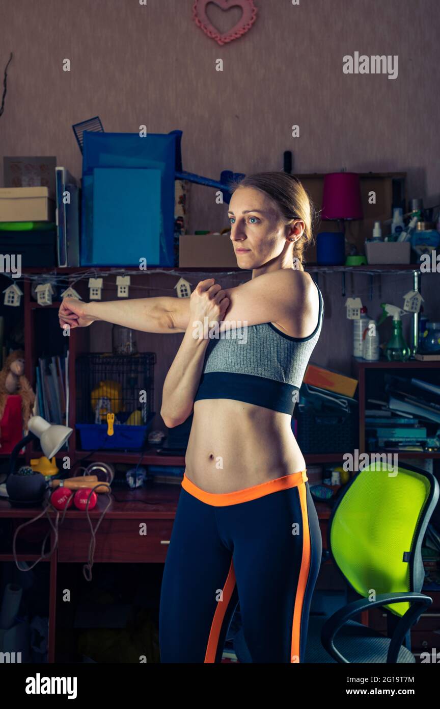 Une petite fille mince entre pour le sport à la maison. Le sport à la maison. Formation près de la table du robot. Cadre vertical. Banque D'Images