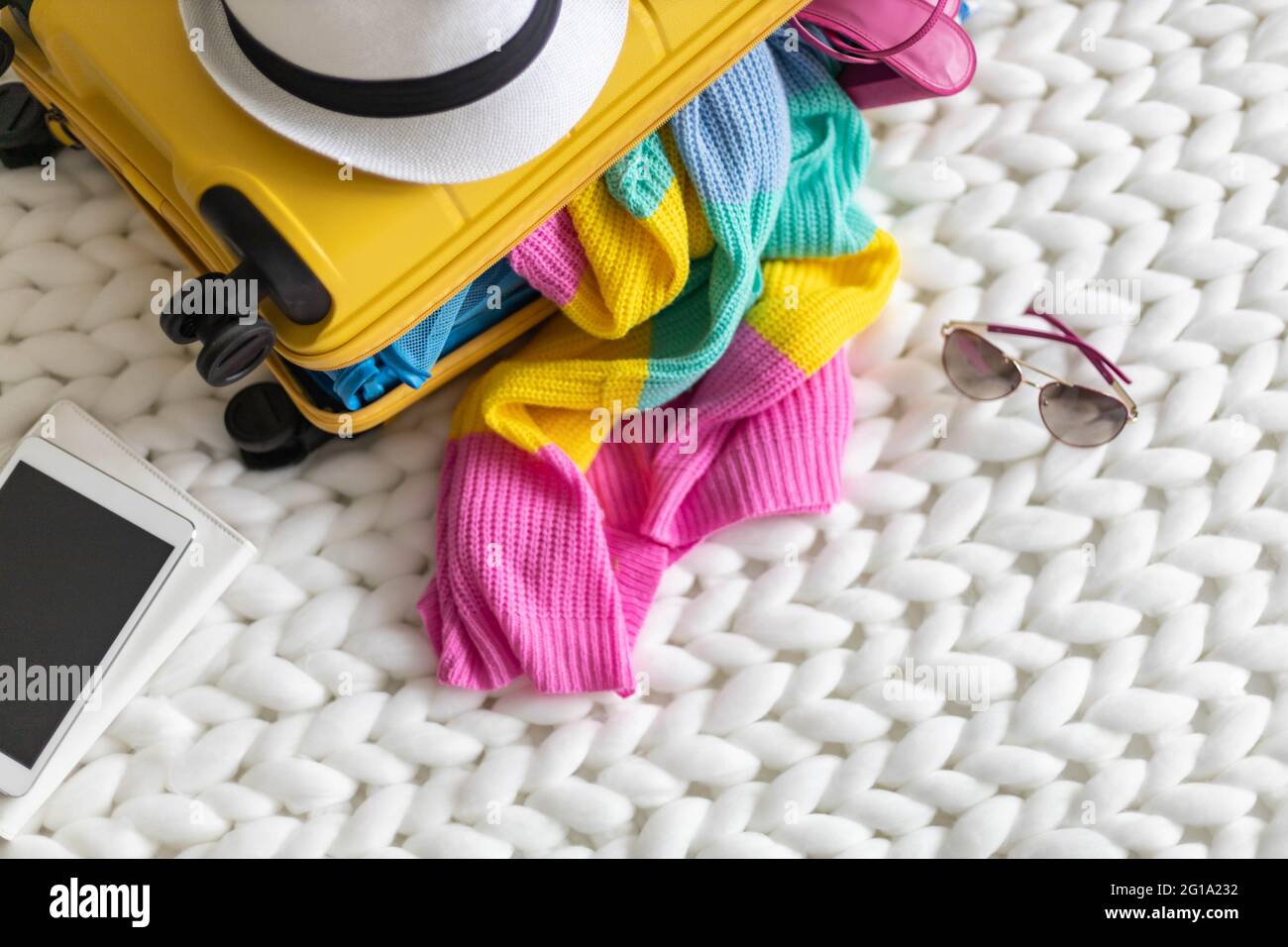 Vue de dessus valise jaune avec les choses nécessaires pour préparer des vacances d'été sur tricoté à carreaux Banque D'Images