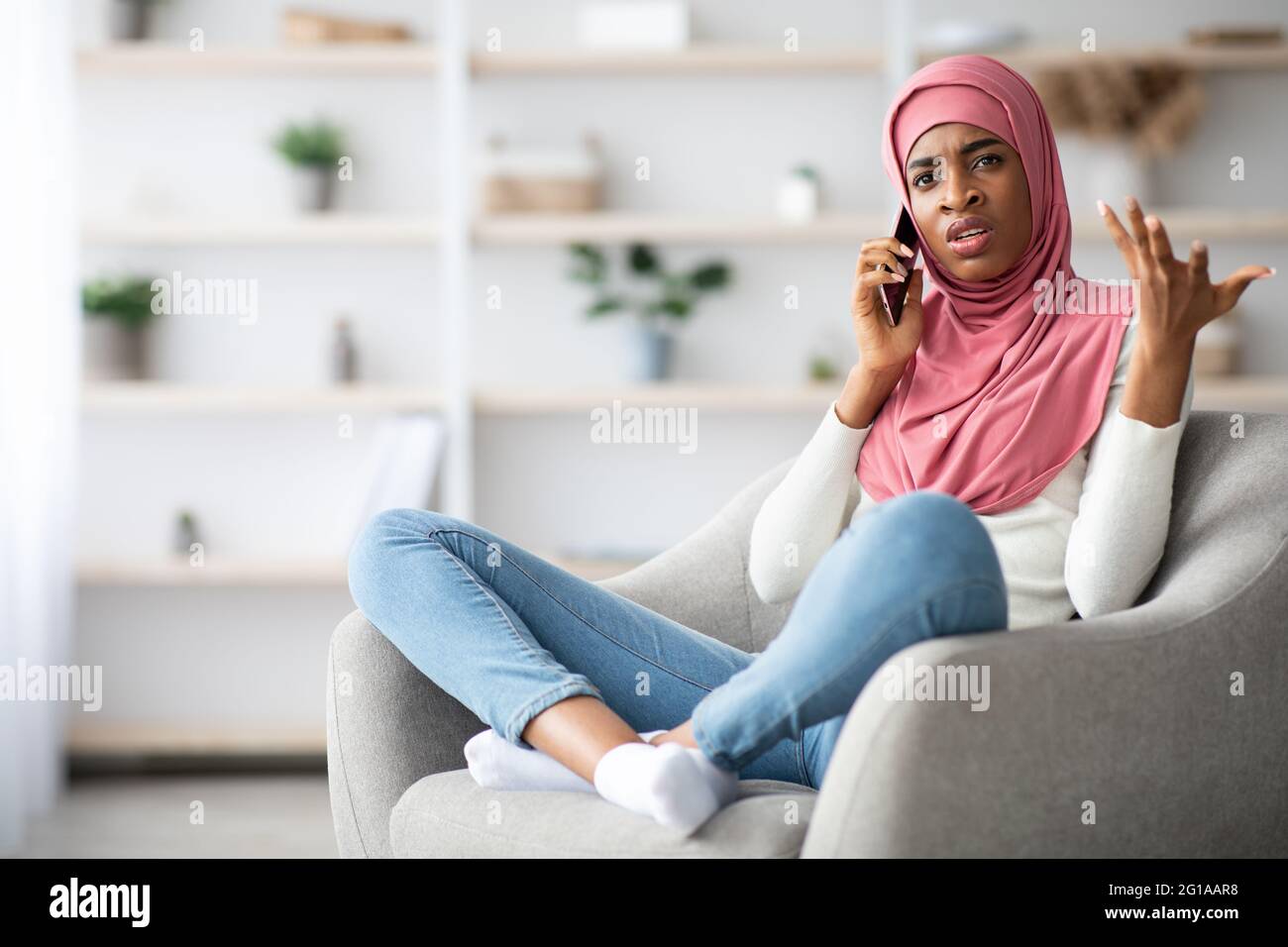 Inquiet Noir musulmane femme dans hijab parlant sur le téléphone portable à la maison Banque D'Images