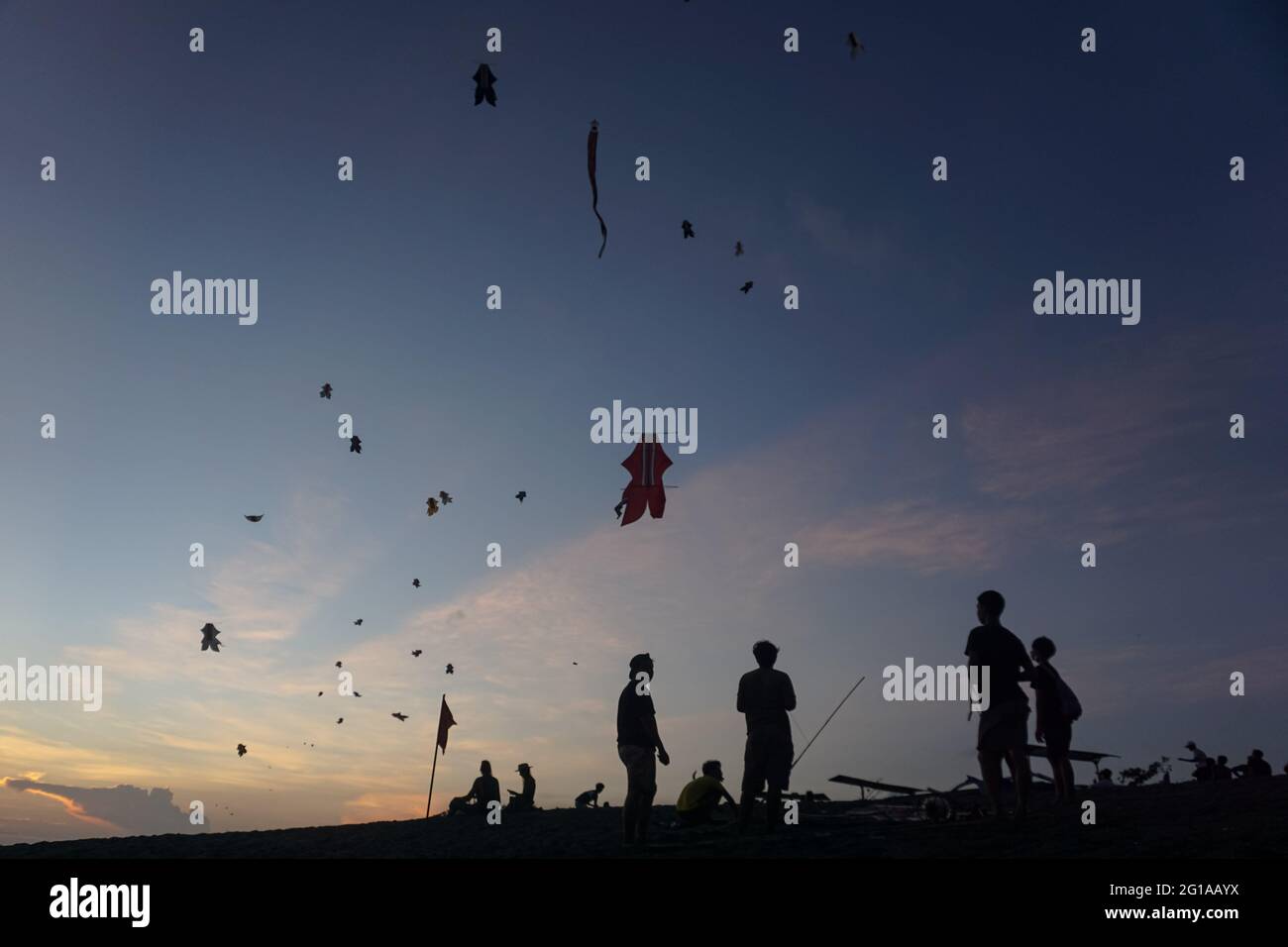 Badung, Bali, Indonésie. 6 juin 2021. La silhouette montre les jeunes balinais voler leur cerf-volant à la plage de Pererenan. La saison des cerfs-volants a lieu de mai à septembre chaque année pendant la saison sèche, et marque le meilleur moment de visite touristique à Bali. Les couleurs du rouge, du blanc, du noir et de l'or jaune représentent l'incarnation des Divinités hindoues balinaises. (Image de crédit : © Dicky BisinglasiZUMA Wire) Banque D'Images