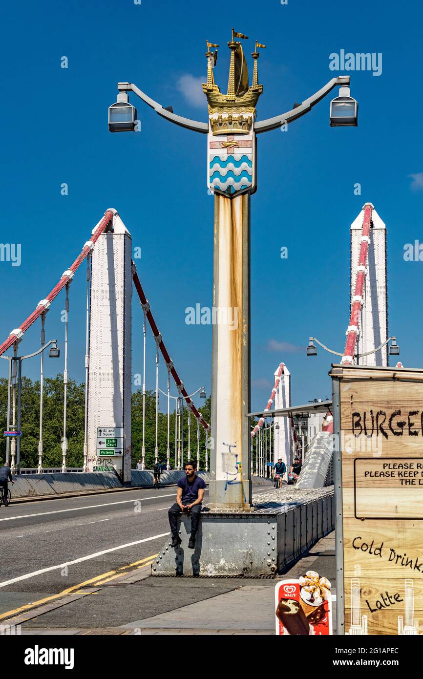 Un homme assis sur le Chelsea Bridge qui a ouvert en 1935 sur la Tamise reliant Chelsea sur la rive nord à Battersea sur la rive sud de Londres Banque D'Images