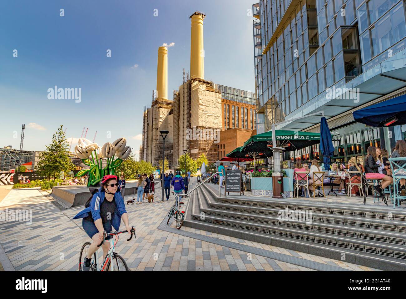 Les personnes dînant dehors, le vélo et la marche au Circus West Village partie du nouveau projet de régénération de la station électrique de Battersea, neuf Elms, Londres UK Banque D'Images