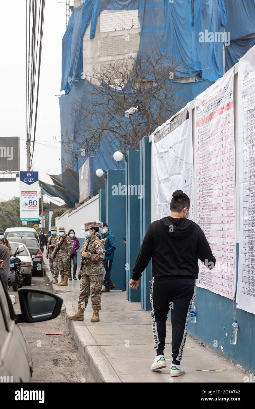 Le 2021 juin jour du vote. Jeune péruvien qui vérifie les listes électorales au bureau de vote alors que la police et les forces armées sont à la porte. Banque D'Images