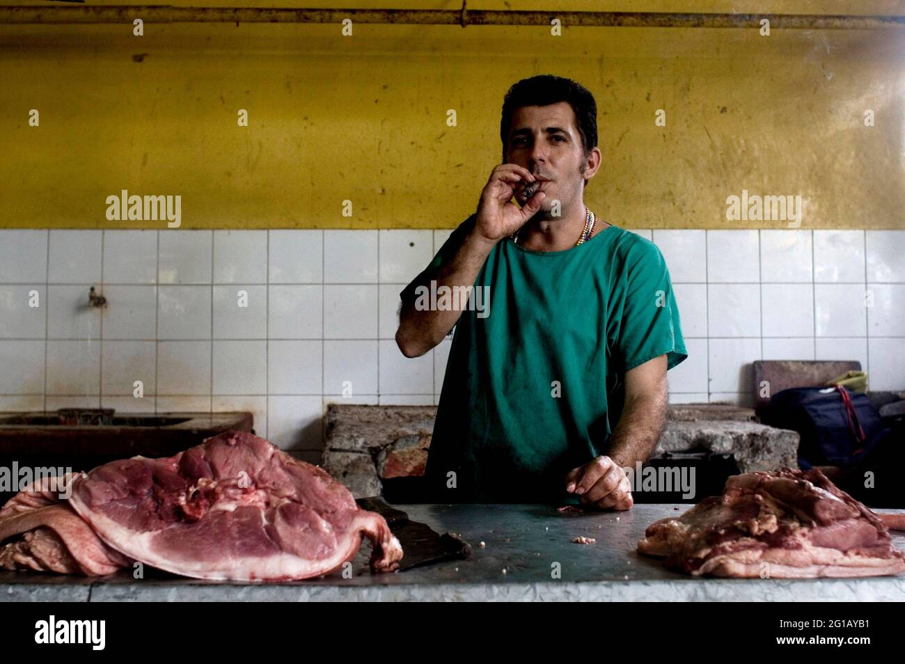 Un homme fumant un cigare à sa boucherie. La ville de la Havane, 50e anniversaire de la révolution socialiste. Cinquante ans depuis la chute du gouvernement Batista. Tout comme l'État révolutionnaire socialiste, sous les troupes de Fidel Castro, Che Guevara et Camilo Cienfuegos. En 2009, alors que la société cubaine reste en constante adaptation et que le régime est entré dans une nouvelle période post-soviétique sociale et économique, Cuba reflète la nécessité de changements révolutionnaires actuels. La Havane, Cuba. 28 février 2008. Banque D'Images