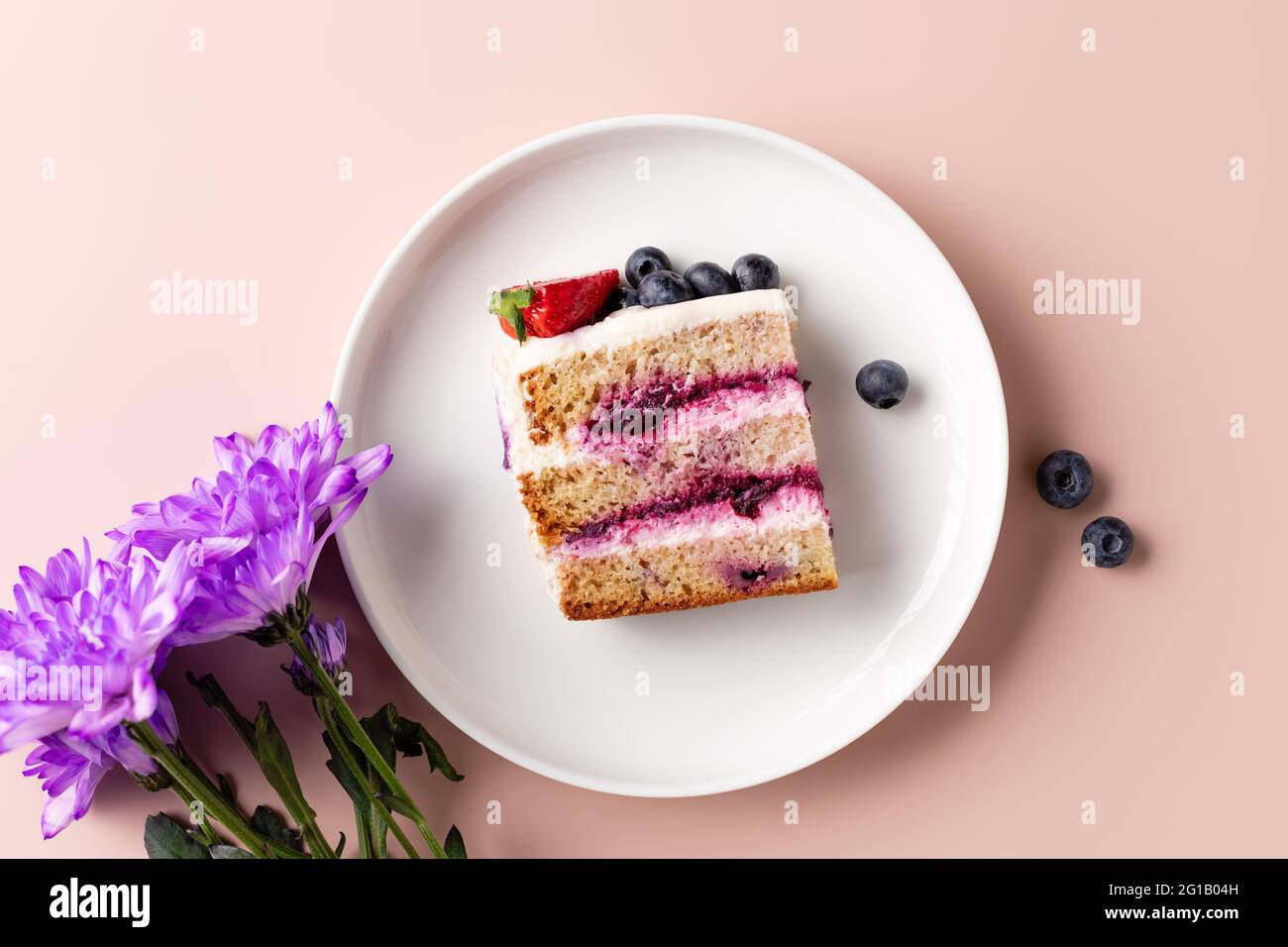 tranche de gâteau aux myrtilles sur assiette blanche et bouquet de fleurs Banque D'Images