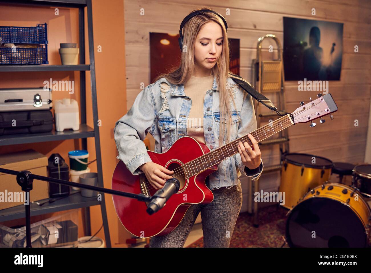 Fille à cheveux longs blonds jouant de la guitare électrique en studio Banque D'Images