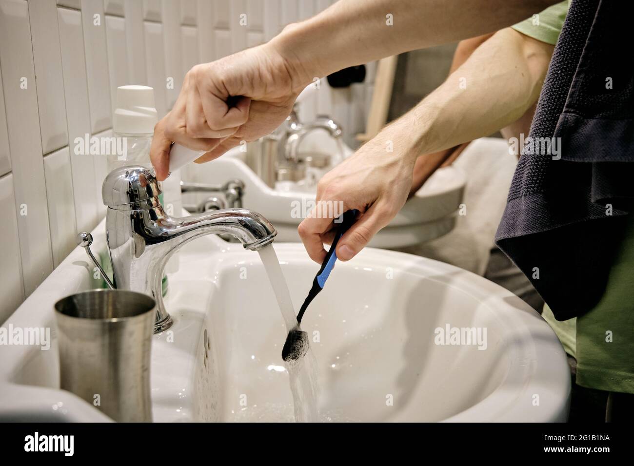 Mains d'un jeune homme avec brosse à dents sur lavabo dans la salle de bains Banque D'Images