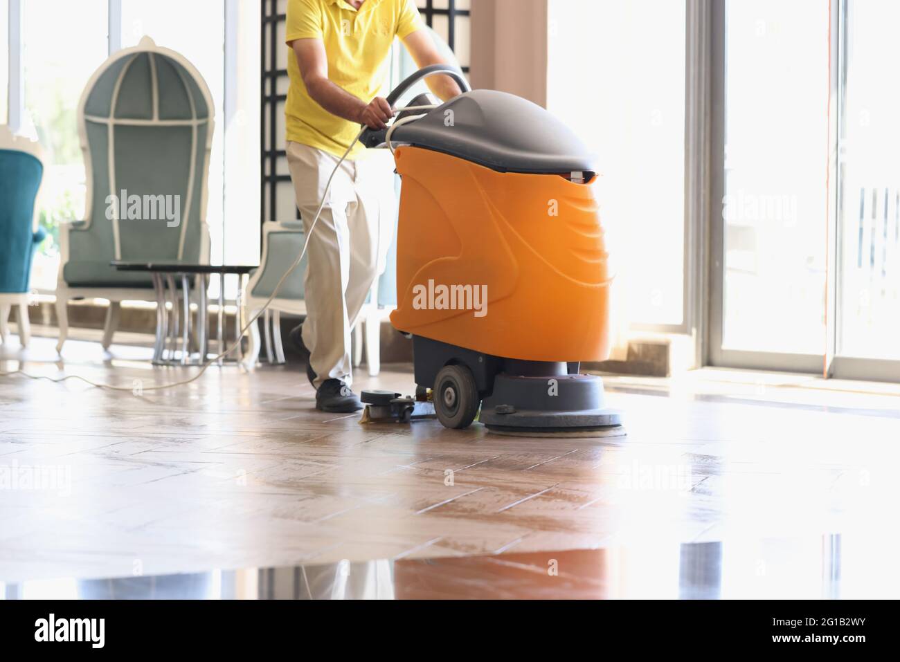 L'homme nettoie le hall de l'hôtel avec un aspirateur industriel Banque D'Images