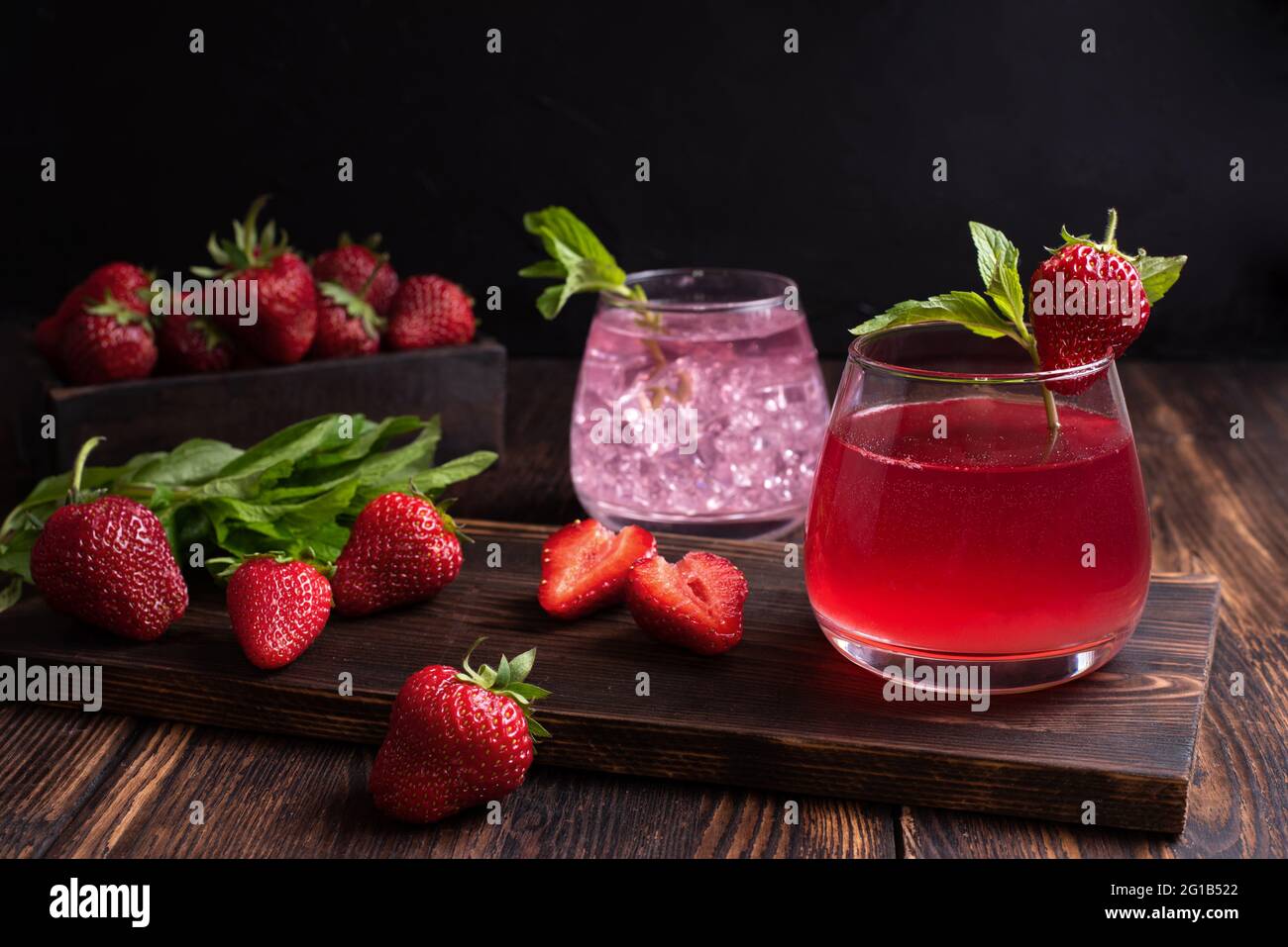 Eau de fruits, limonade aux fraises avec branche de menthe et fraises sur fond de bois, concept de boissons rafraîchissantes en été, gros plan. Banque D'Images