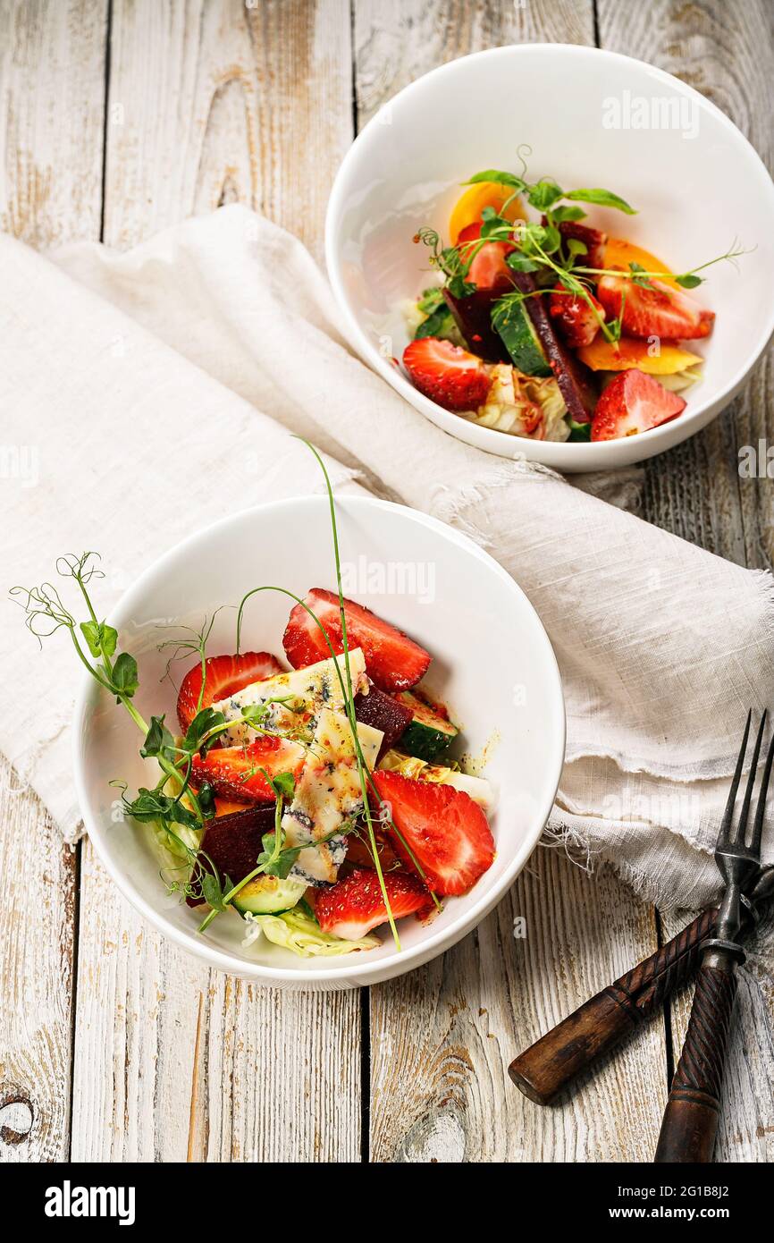 Vue de dessus délicieuse salade d'été.Salade de fraises fraîches, betteraves cuites au four, tomates jaunes, fromage bleu et herbes dans un bol blanc Banque D'Images