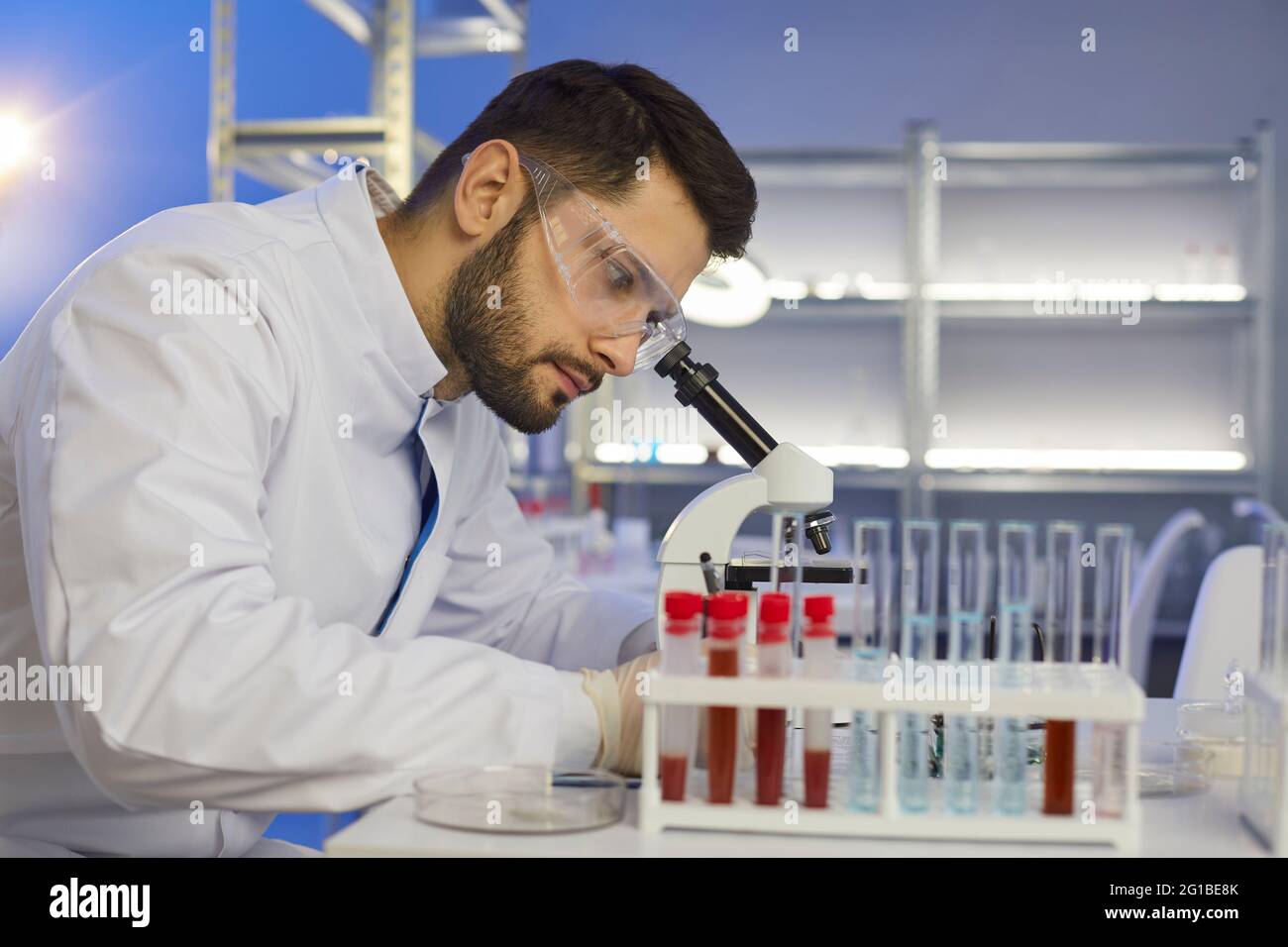 Scientifique regardant un échantillon au microscope dans un laboratoire pharmaceutique ou de microbiologie Banque D'Images