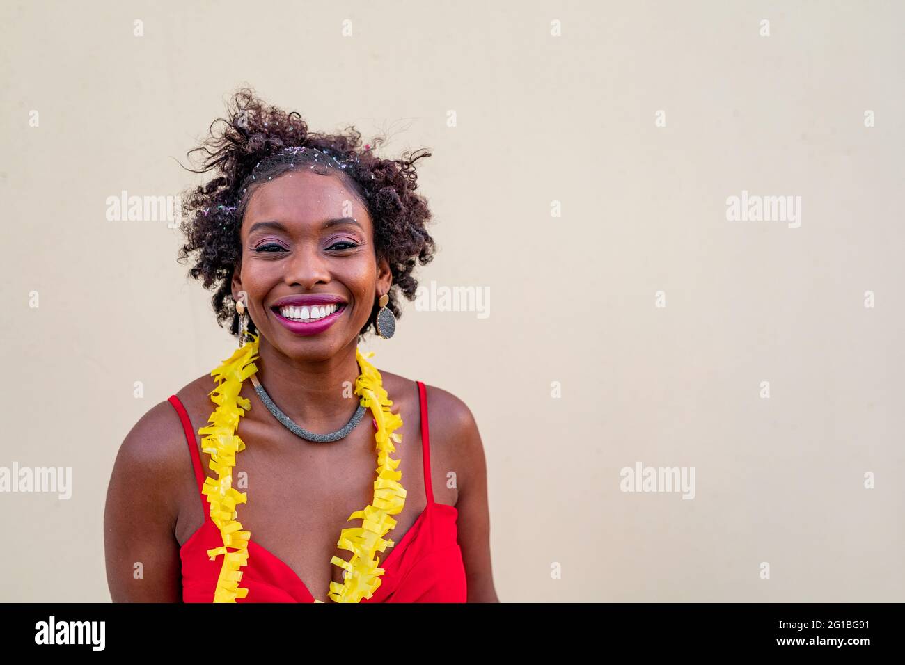 Bonne femme afro-américaine debout près du mur blanc et regardant la caméra Banque D'Images