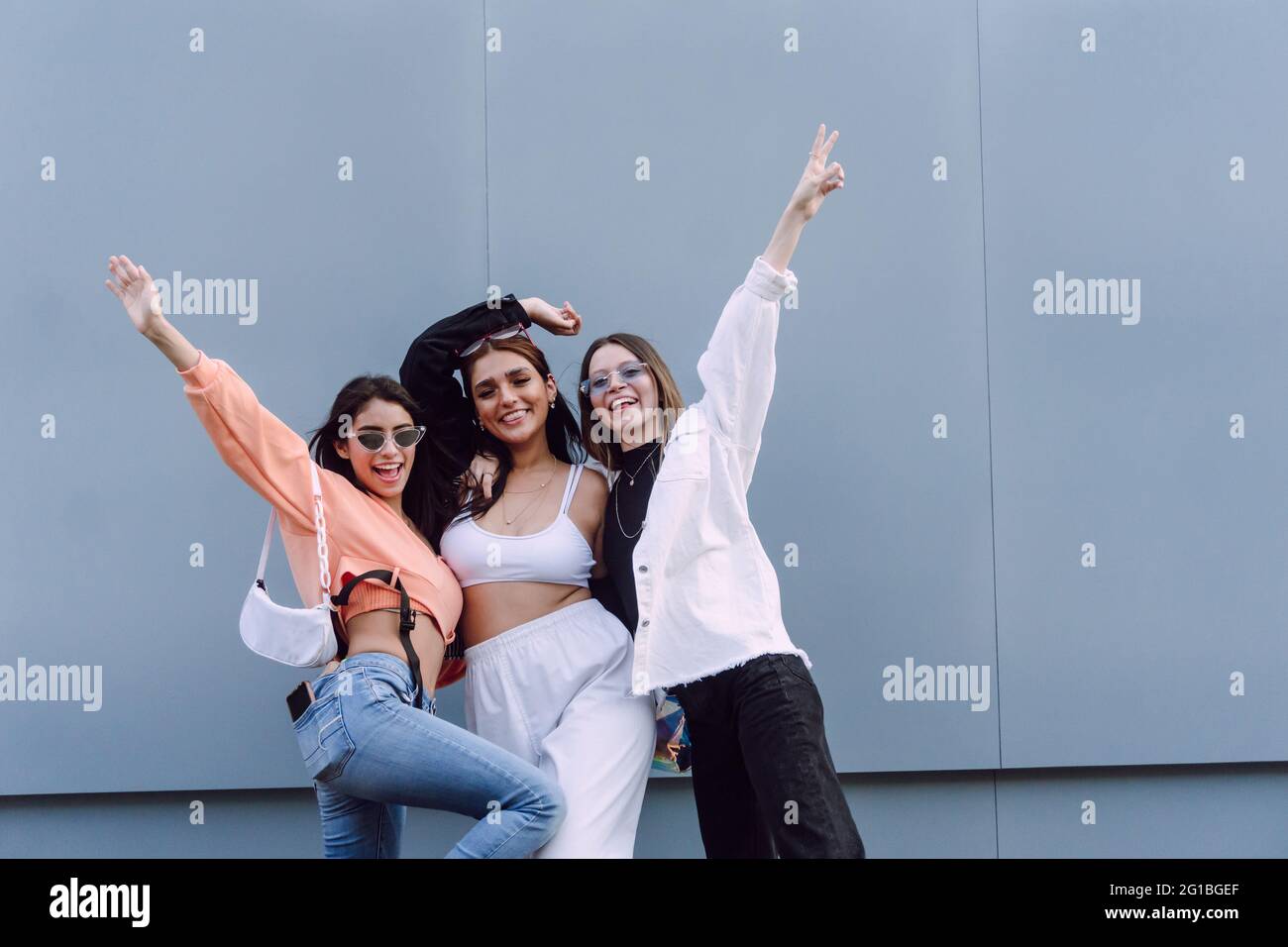 Des amies positives dans des lunettes de soleil tendance et des vêtements décontractés riant heureux tout en passant un agréable temps ensemble Banque D'Images