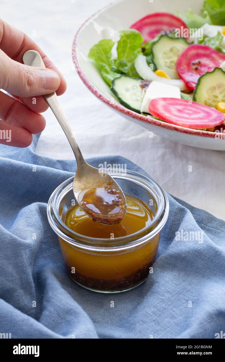 Grand angle de récolte mâle anonyme avec cuillère dans un bol en verre avec miel placé sur la table à côté de la salade végétarienne avec concombre et betterave avec l vert Banque D'Images
