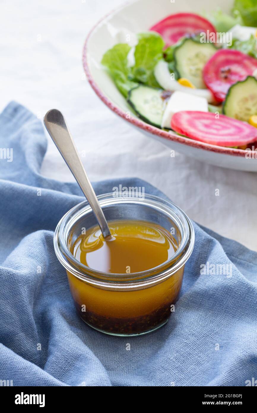 Cuillère à grand angle dans un bol en verre avec du miel placé sur la table à côté de la salade végétarienne avec concombre et betterave avec feuilles vertes et maïs Banque D'Images