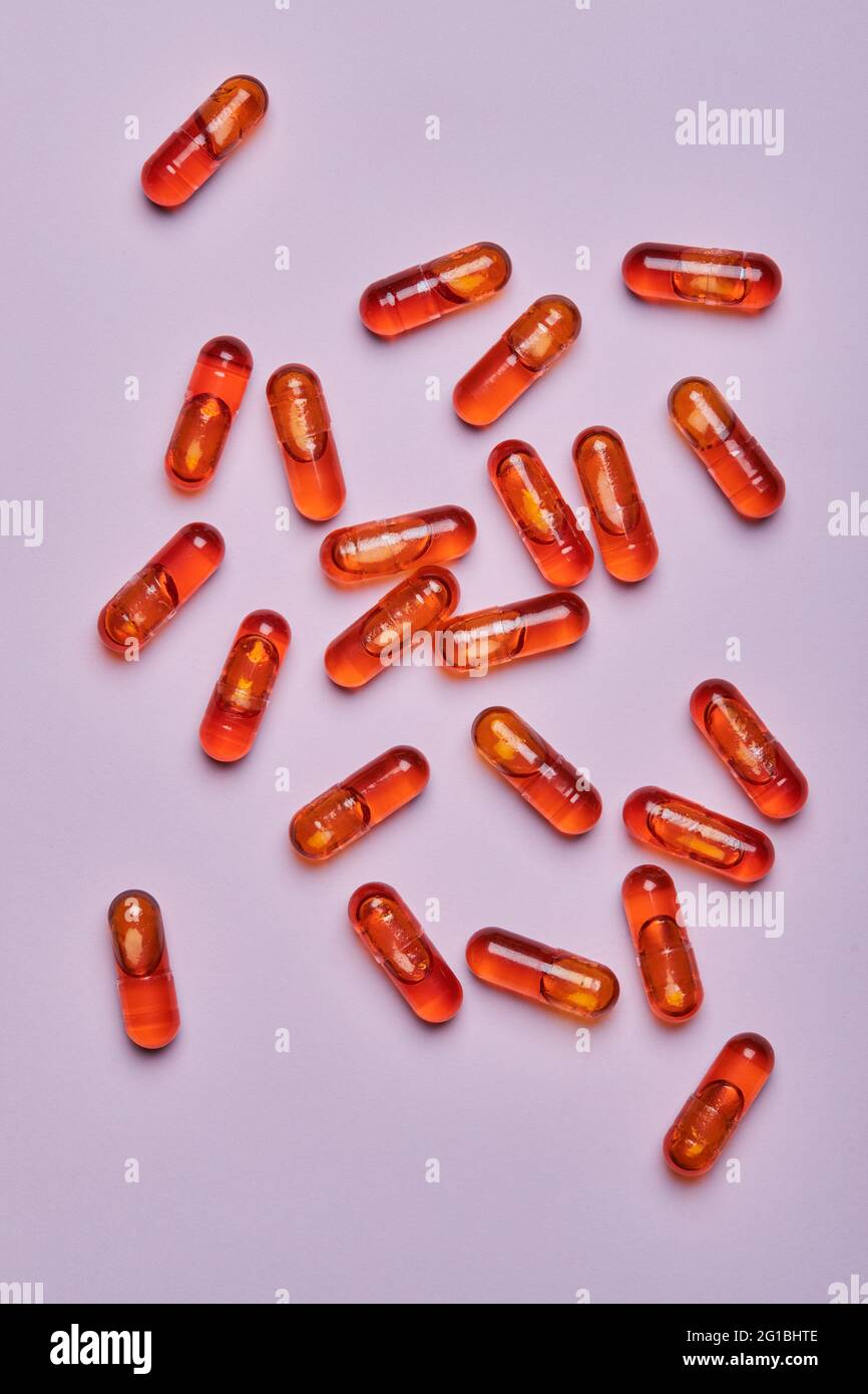 Vue de dessus composition de pilules orange éparpillées sur fond rose en studio léger Banque D'Images