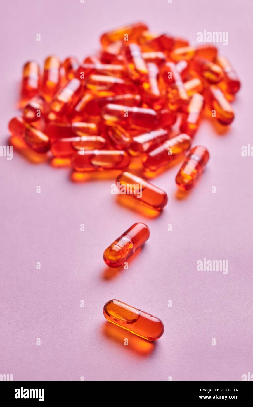 Composition de pilules d'orange dispersées sur fond rose en studio léger Banque D'Images