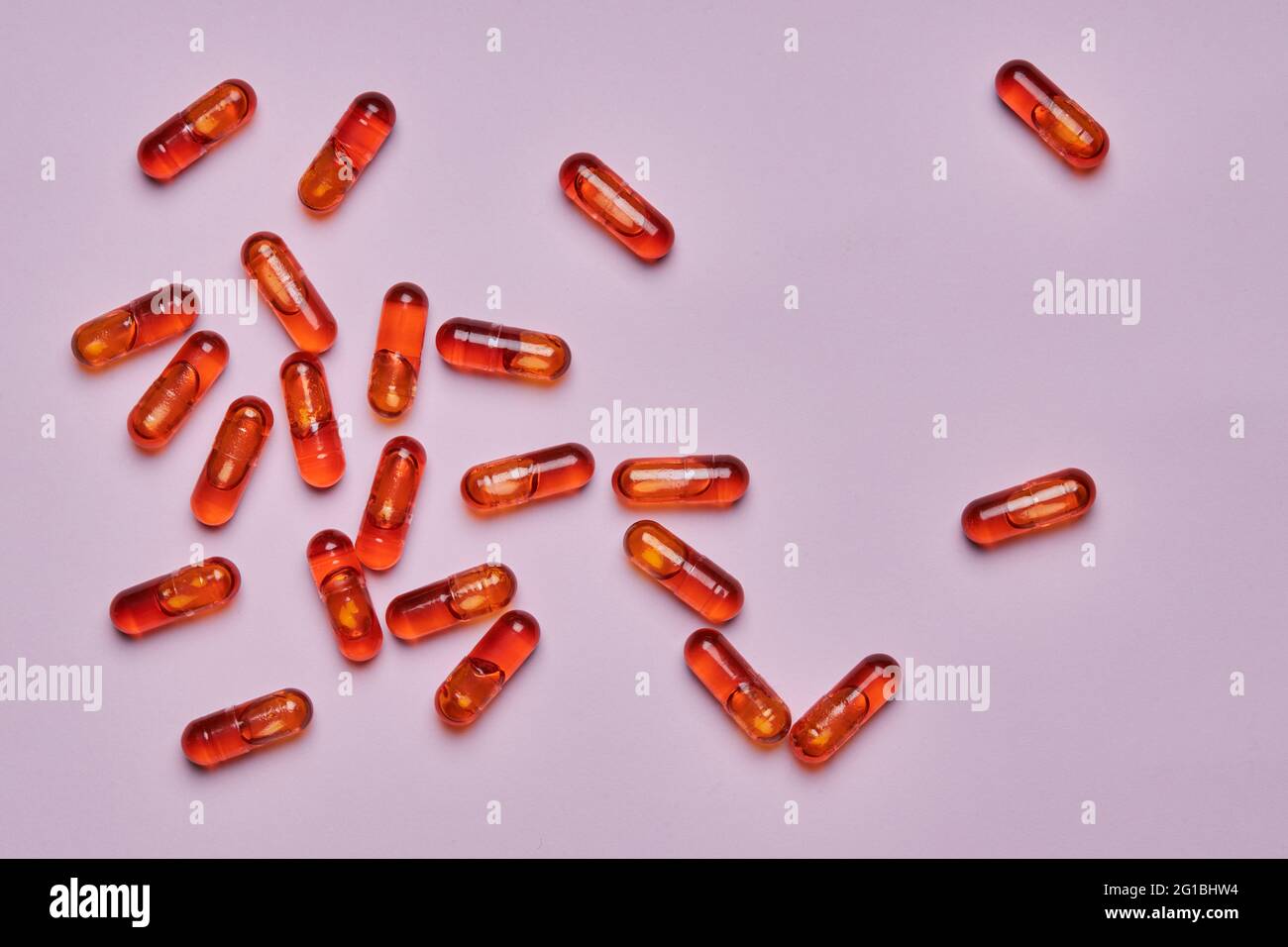 Vue de dessus composition de pilules orange éparpillées sur fond rose en studio léger Banque D'Images