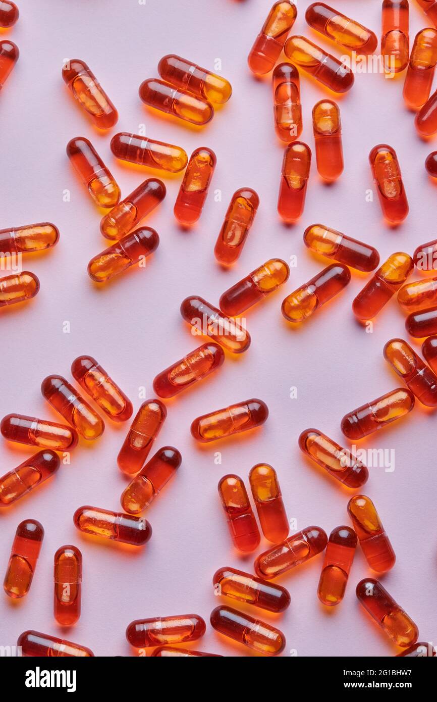 Vue de dessus composition de pilules orange éparpillées sur fond rose en studio léger Banque D'Images