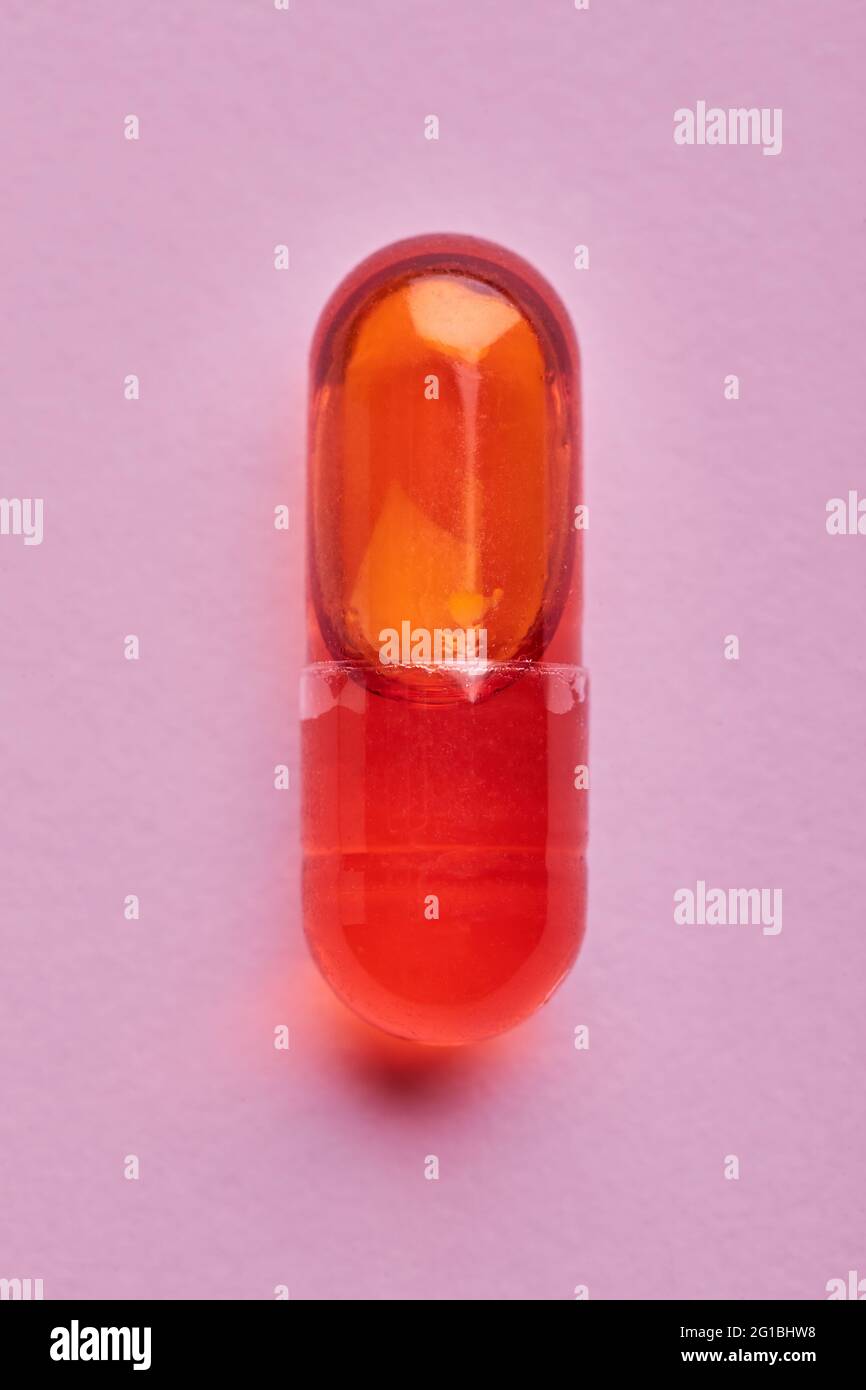 Composition de pilules orange sur fond rose en studio léger Banque D'Images