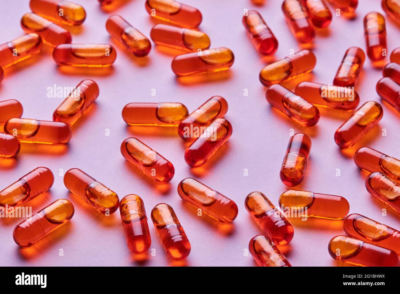 Vue de dessus composition de pilules orange éparpillées sur fond rose en studio léger Banque D'Images
