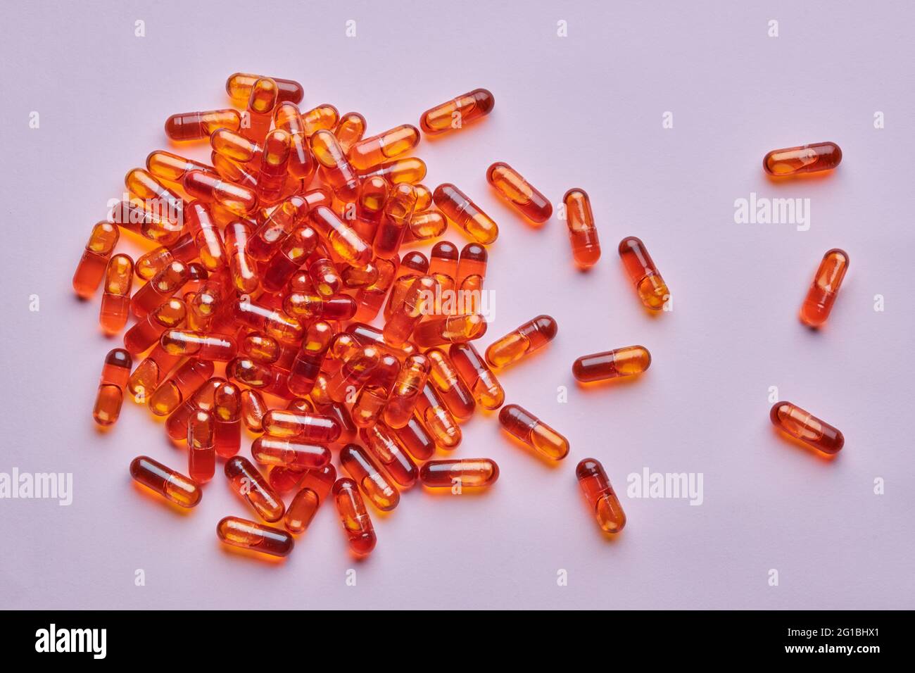 Vue de dessus composition de pilules orange éparpillées sur fond rose en studio léger Banque D'Images