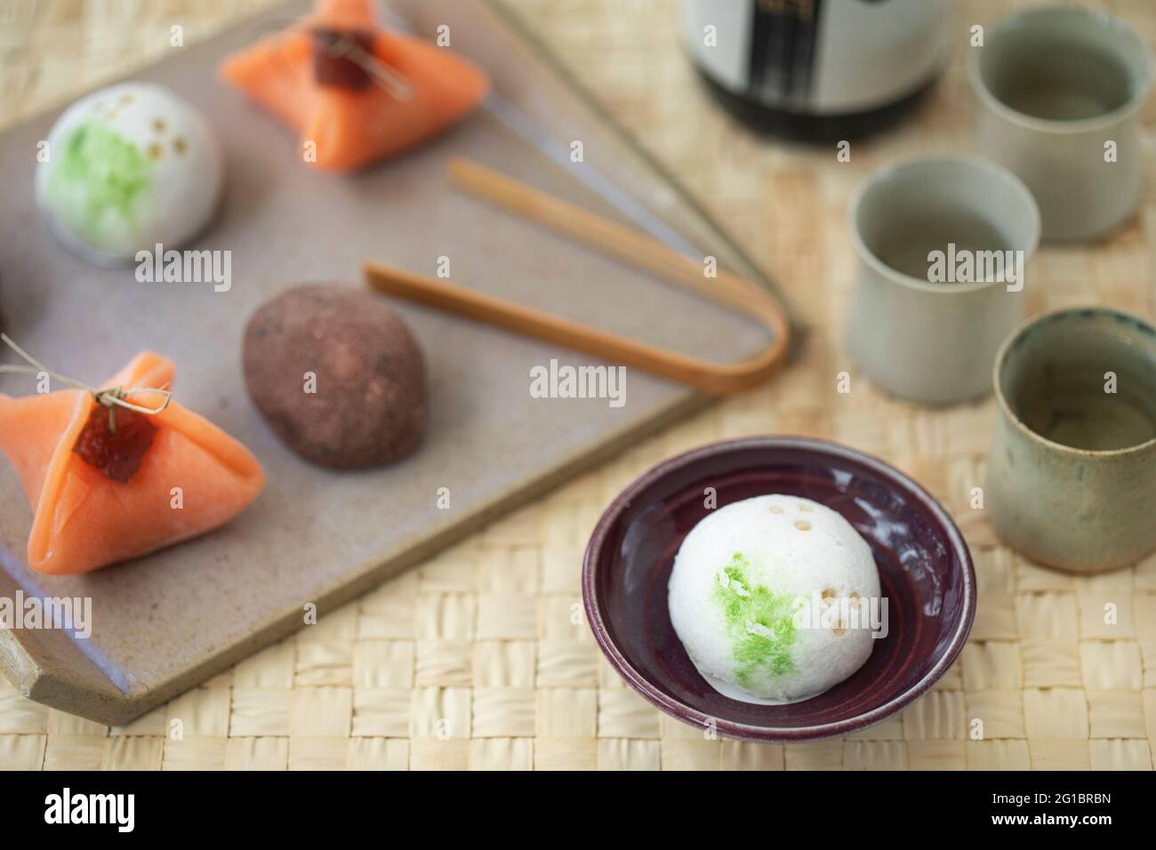 Plateau en céramique avec de petites sucreries japonaises wagashi et de petites tasses en céramique de saké. Banque D'Images