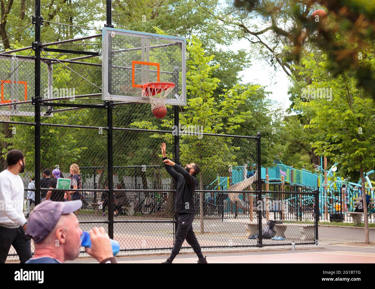 un homme afro-américain se retrouve pour le basket-ball alors qu'il tombe du panier de basket-ball sur un terrain de basket-ball du parc de la ville de new york Banque D'Images