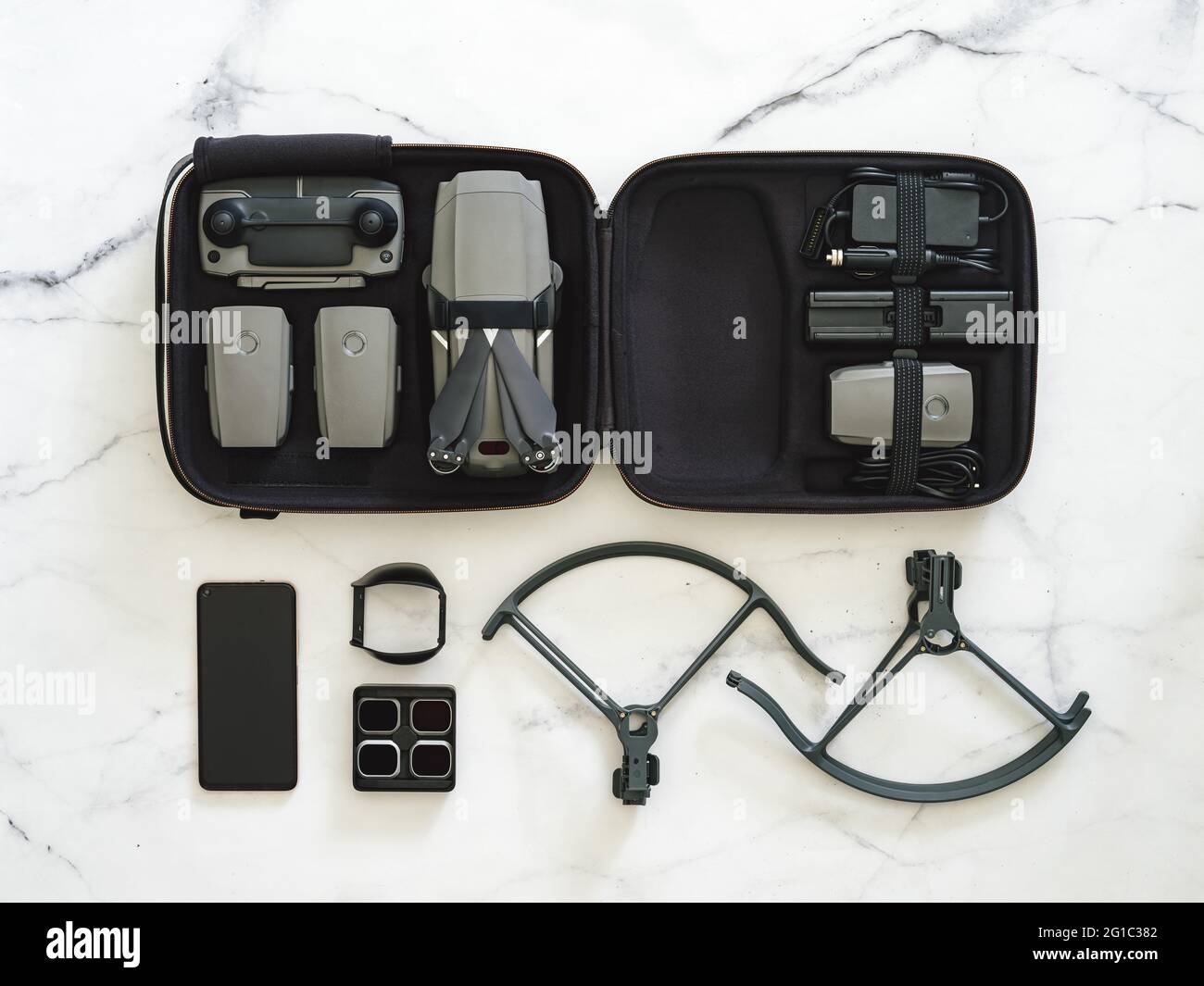 Drone pliant. Équipement de drone avec jeu complet sur fond de marbre blanc. Style minimaliste. Vue de dessus. Pose à plat. Kit de drone UAV en étui et accessoires. Concept d'équipement de tournage Banque D'Images