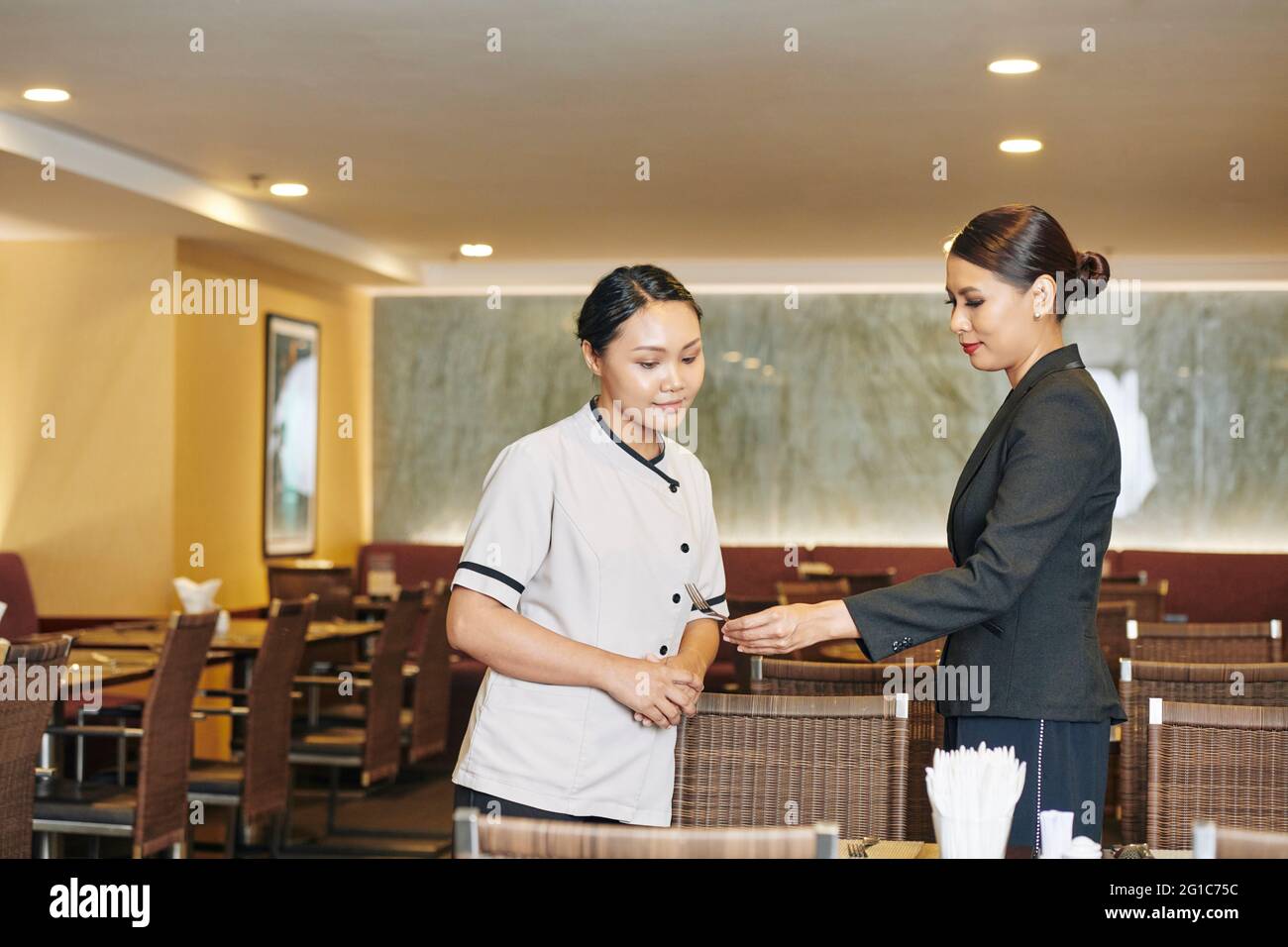 Le directeur du restaurant se tient à table et montre une fourchette sale à la serveuse Banque D'Images