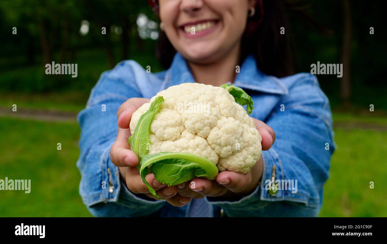 Bonne femme végétarienne, femme au foyer garde le chou-fleur frais dans son jardin biologique et sourit, fermier avec le chou-fleur pendant la récolte. Alimentation saine alimentation végétarienne légumes gros plan Banque D'Images