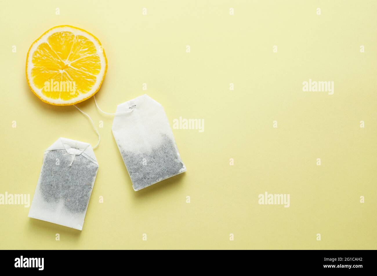 Sachets de thé et une tranche de citron sur fond jaune Banque D'Images