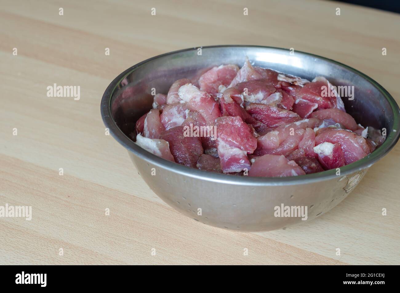 Préparation étape par étape de jambon haché fait maison. Étape 1: Saler la viande pour le jambon. Un bol de morceaux de viande, de sel, d'ail et de poivre sur le tabl Banque D'Images