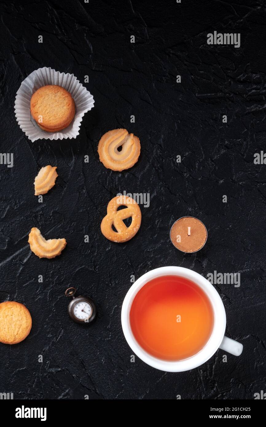 Biscuits au beurre danois avec thé, tiré du haut sur un fond noir avec un endroit pour le texte Banque D'Images