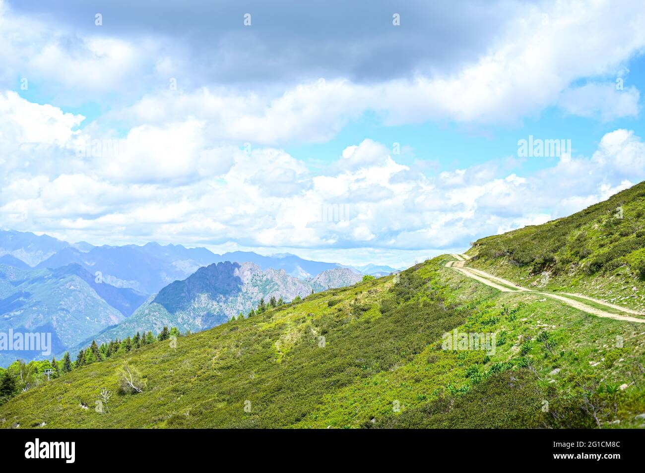 Une piste plate de randonnée en terre entourée de pâturages verts sur le plateau de l'Alpe di Mera à Valsemia, Piémont, Italie en été Banque D'Images