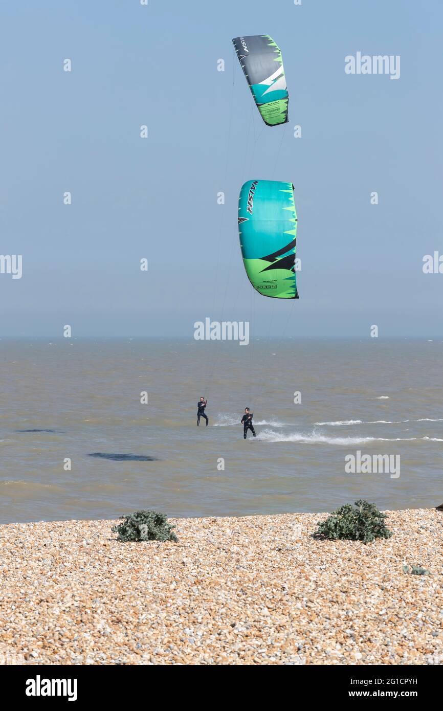 Kite Surfers qui s'accélère le long de la côte à Dungeness, Kent, Angleterre, Royaume-Uni. Banque D'Images