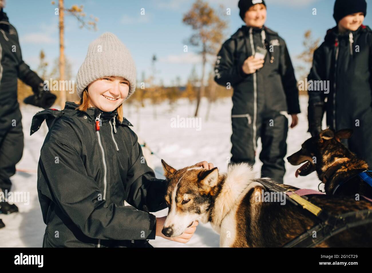 Portrait d'une adolescente souriante qui a caressé un chien husky pendant l'hiver Banque D'Images