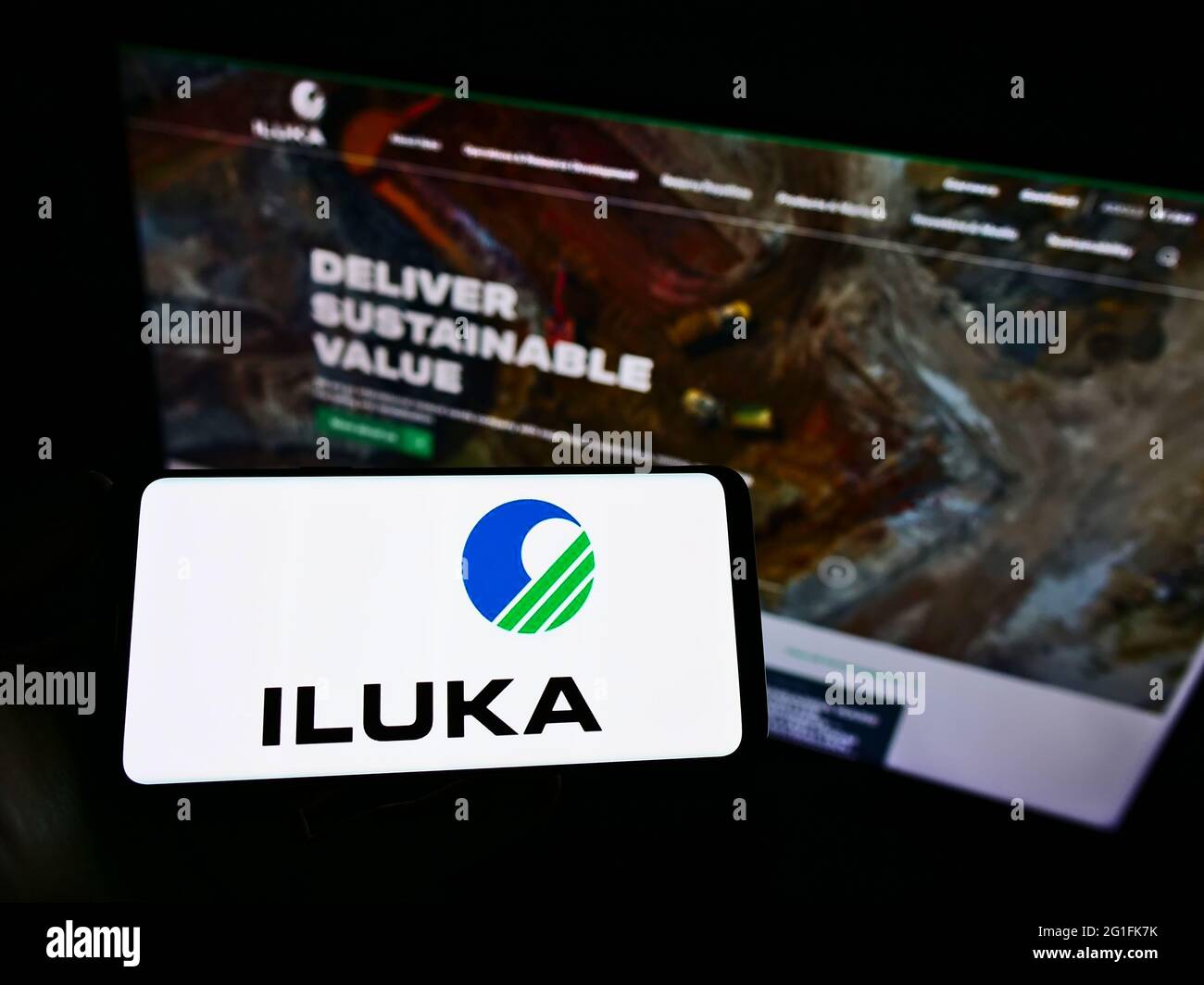 Personne tenant un téléphone portable avec le logo de la société minière australienne Iluka Resources Limited à l'écran devant la page Web. Mise au point sur l'affichage du téléphone. Banque D'Images