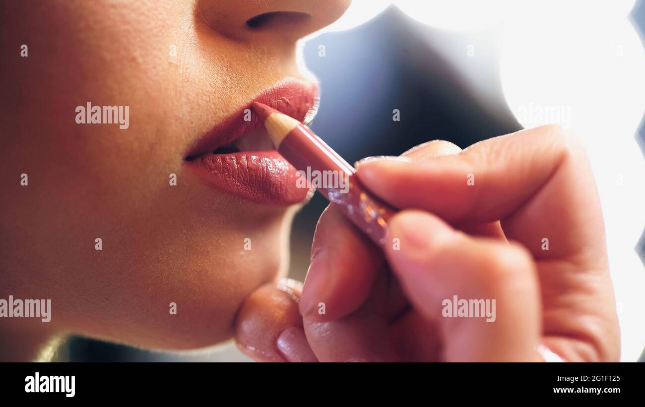 vue rognée d'un maquilleur appliquant un crayon à lèvres sur les lèvres du modèle Banque D'Images