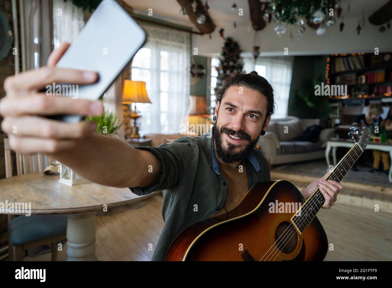 Jeune hispanique jouant de la guitare à la maison avec un ordinateur portable Banque D'Images