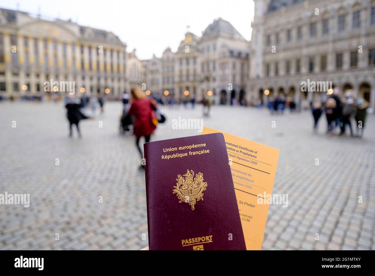 Belgique, Bruxelles, le 19 février 2021 : voyageur français avec son passeport et un certificat international de vaccination ou de prophylaxie dans une rue de Banque D'Images