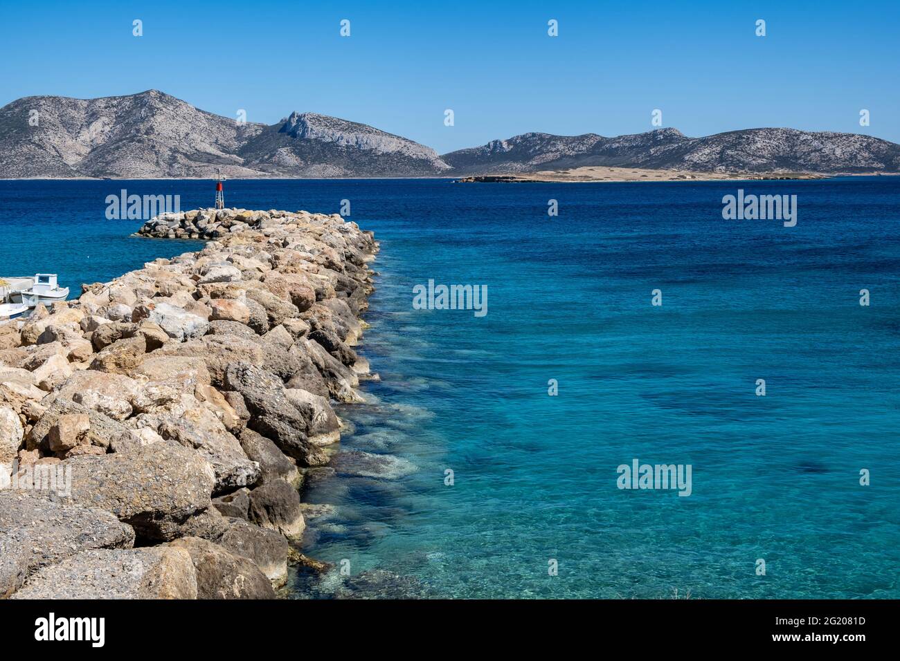 Vue sur le petit-déjeuner et la balise aérienne de drone. Île de Koufonisi port de plaisance mur de protection rocailleux, petits Cyclades Grèce. Mer rippée et ciel bleu clair Banque D'Images