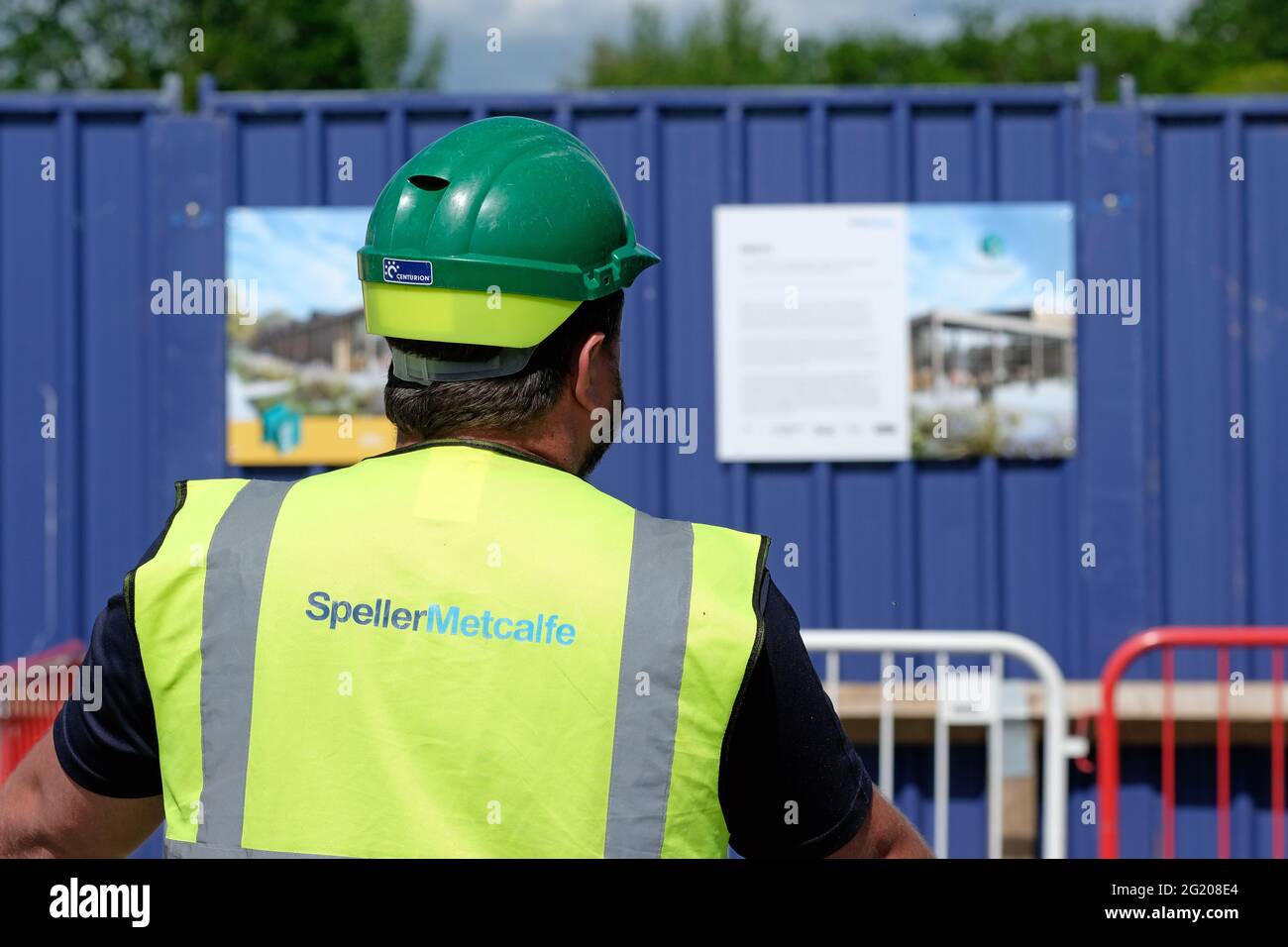 Un constructeur portant un casque de sécurité et une veste haute viz avec des titres de Speller Metcalfe au Royaume-Uni Banque D'Images